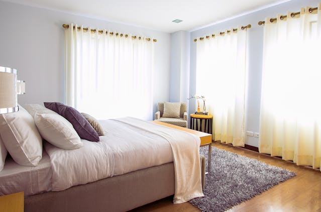 a bedroom with two large windows, floor-to-ceiling curtains and a large bed
