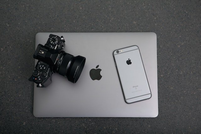 a camera and cellphone resting on top of a closed laptop