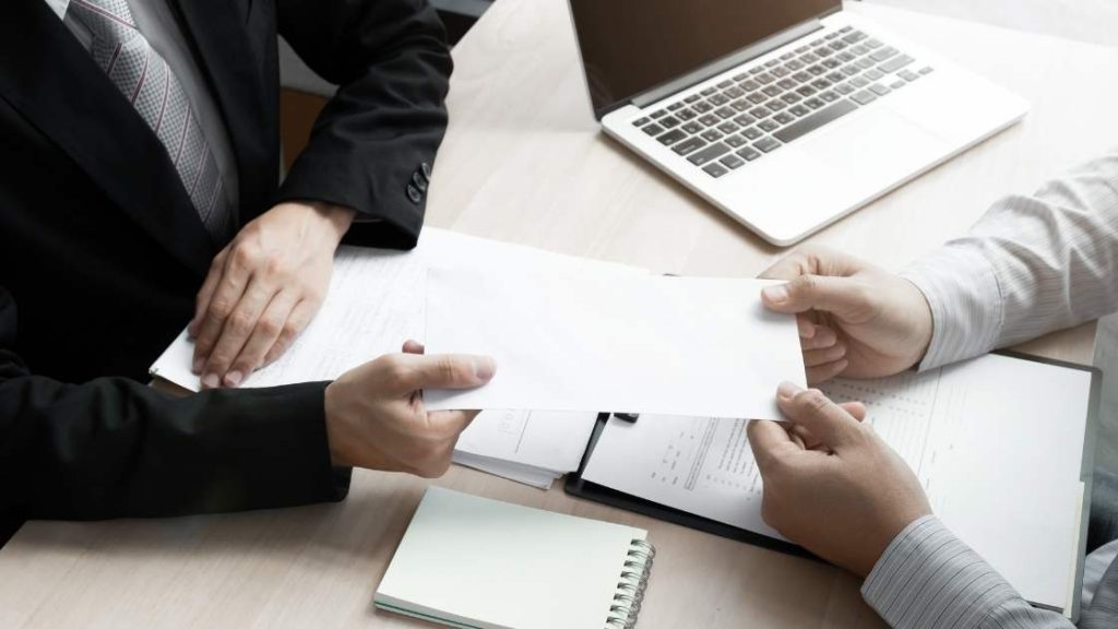 two people holding onto the same document as they pass it back and forth